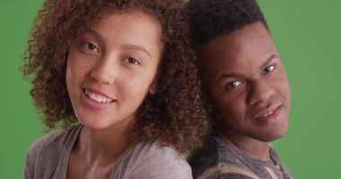 Mutlu gülümseyen Afro-Amerikan erkek ve kadın yeşil ekranda birbirlerine yaslanıyorlar. Anahtar ya da birleşik olmak üzere yeşil ekranda.