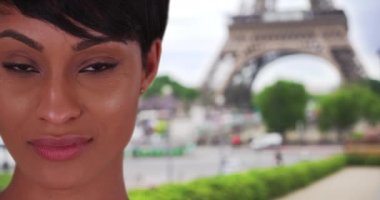 Güzel, genç bir Afrikalı kadın Paris 'te Eyfel Kulesi' nin yanında dikilirken kameraya dikkatle bakıyor. Paris 'te bir caddede genç ve siyah bir güzelin şehvetle bakışları. 4k