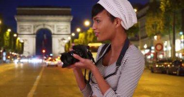 Genç Afrikalı kadın fotoğrafçı Paris, Fransa 'da Zafer Takı yakınlarında fotoğraf çekiyor. Paris 'te sokakta fotoğraf çeken kameralı siyahi bir kadın. 4k