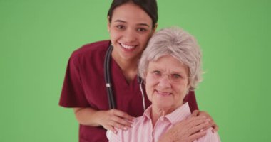 Yeşil ekranda portre için gülümseyen yaşlı bir hastası olan kadın hemşire ya da bakıcı. Latin kadın bakım uzmanı profesyonel ve son sınıf öğrencisi birleşim için yeşil ekranda. 4k