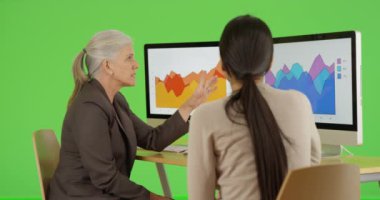 İki iş kadını yeşil ekranda grafikleri tartışıyor. Anahtar ya da birleşik olmak üzere yeşil ekranda.