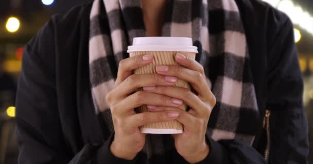 夕方には屋外でコーヒーカップを保持黒の女性の手の閉鎖 ホットドリンクで手を暖めるスタイリッシュなスカーフで若い女性のクローズアップ — ストック動画