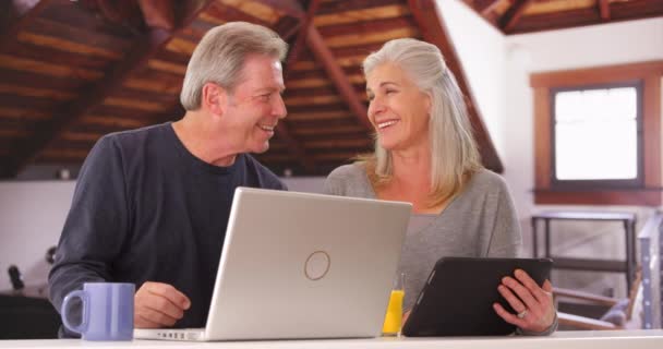 ハイテク機器を見て魅力的な白いカップルの肖像画 自宅で携帯電話を使っている2人の高齢者 — ストック動画