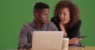 Yeşil ekranda dizüstü bilgisayarda çalışan iki siyah iş adamı. Anahtar ya da birleşik olmak üzere yeşil ekranda.