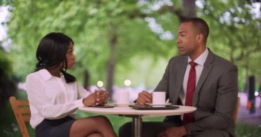 Bir çift şirket ortağı iş meselesini kahve içerken tartışıyor. Genç siyahi iş adamı, iş arkadaşlarının iş istatistiklerini tabletinde gösteriyor. 4k