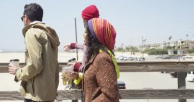 Genç kalça çok ırklı arkadaşlar bir rıhtımdan sahile doğru yürüyorlar.