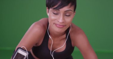 Koşudan sonra gülümseyen ve soluklanan genç siyahi kadın yeşil ekrandaki kameraya bakarken soluklanıyor. Anahtar ya da birleşik olmak üzere yeşil ekranda.