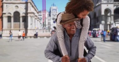 Afro-Amerikalı çift gülümseyip St. Mark Meydanı 'nda eğleniyor. Venedik Plaza 'da turizmle mutlu siyah kadınlar sırtına biniyor. 4k