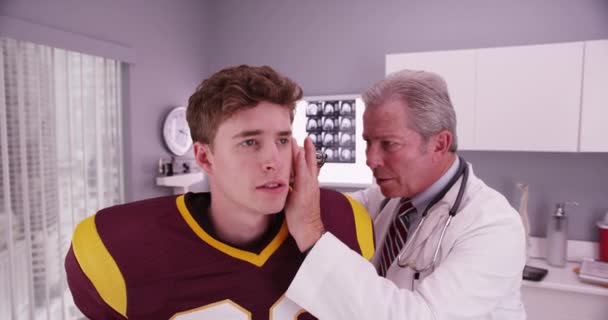 スポーツ選手の耳を調べる先輩医師 — ストック動画