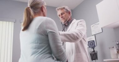 Erkek kıdemli Doktor hastanın hayati stetoskop ile dinleme