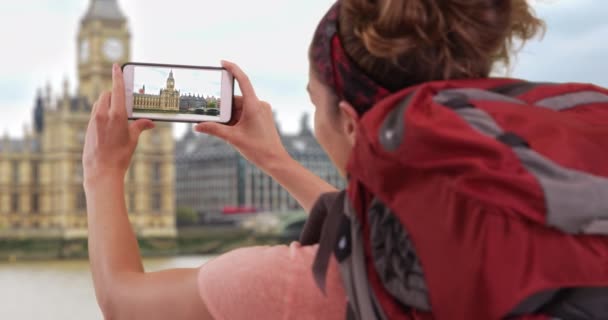 イギリスのロンドンを探検している若い女性が 携帯電話でビッグ ベンのビデオを録画しています スマホでビッグ ベンの白人女性観光客撮影動画 — ストック動画