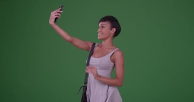 Bir kadın öpüşüyor ve yeşil ekranda akıllı telefonuyla selfie çekiyor. Anahtar ya da birleşik olmak üzere yeşil ekranda.