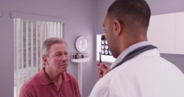 Beyin sarsıntısı geçiren genç bir doktorla yaşlı bir erkek hasta.