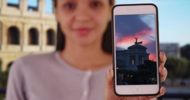 Latina Millennial, Altare della Patria 'nın akıllı telefonundaki fotoğrafını gösteriyor. Roma 'daki İspanyol kız telefonunda Monumento Nazionale' nin Vittorio Emanuele II resmi var. 4k