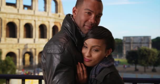2人のアフリカ系アメリカ人の恋人は イタリアのローマでロマンチックな休暇にお互いを保持しています ローマのコロッセオ近くで抱擁する若い黒人夫婦を愛しています — ストック動画