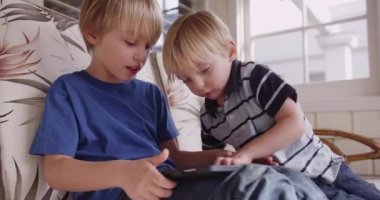 Beyaz iki genç bir tablet ile oynayan çocuklar