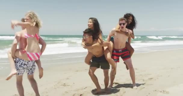Šťastná Skupina Mladých Mezirasových Přátel Piggyback Jízda Pláži — Stock video