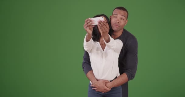 一对年轻的非洲裔美国夫妇摆出可爱的姿势 在绿色的屏幕上亲吻自己 在绿色屏幕上键入或合成 — 图库视频影像