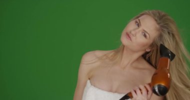 Beyaz kız saçlarını yeşil ekranda kurutur ve tarar. Anahtar ya da birleşik olmak üzere yeşil ekranda.