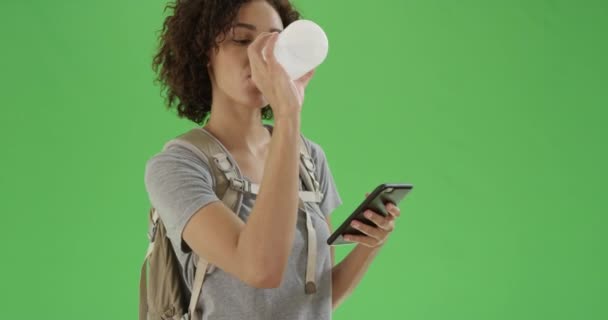 Młoda Czarna Dziewczyna Rozgląda Się Trzymając Swój Smartfon Butelkę Wody — Wideo stockowe