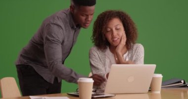 İki siyah iş adamı yeşil ekranda kahve içerken dizüstü bilgisayarda çalışıyor. Anahtar ya da birleşik olmak üzere yeşil ekranda.