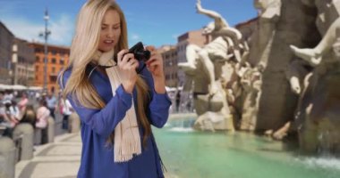 Güzel beyaz kadın Roma 'da seyahat ederken kamerasıyla fotoğraf çekiyor. Roma, İtalya 'daki Kafkasyalı turist, memleketteki insanlara göstermek için Fiumi çeşmesinin yanında fotoğraf çekiyor. 4k