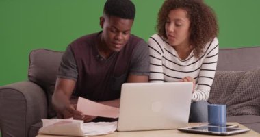 Siyah milenyum çifti yeşil ekranda dizüstü bilgisayarla fatura ödüyor. Anahtar ya da birleşik olmak üzere yeşil ekranda.