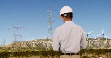 Mühendis, yenilenebilir enerji için rüzgar türbinlerini kontrol ediyor. İspanyol güç işçisi, başlık takıyor ve tablet bilgisayar kullanarak yel değirmenlerini kontrol ediyor. 4k