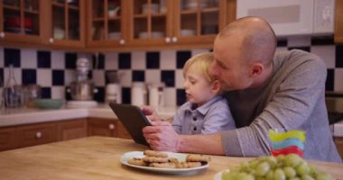 Orta yaşlı beyaz baba bir tablet kullanmak için şirin küçük oğlu öğretim
