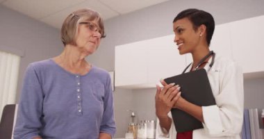 Kadın siyahi doktor, kadın beyaz hastayla sağlığı tartışıyor.