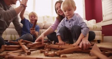 Genç sarışın çocuklar aileleriyle tahta bloklar oynuyorlar.