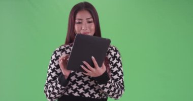 Asyalı kadın yeşil ekranda gece açık havada tablet kullanıyor. Anahtar ya da birleşik olmak üzere yeşil ekranda.