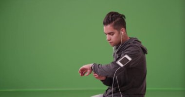 Milenyum İspanyol koşucusu yeşil ekranda dinlenirken spor takip cihazını kontrol ediyor. Anahtar ya da birleşik olmak üzere yeşil ekranda.