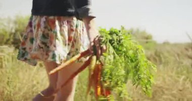 Genç bir kadının taze toplanmış sebzelerle yürüdüğü yakın plan.