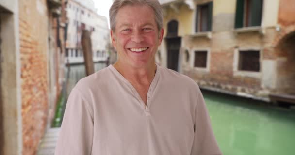 ヴェネツィアを旅する幸せな白人男性 イタリアは彼の休暇を楽しんでいます 熟女は喜んで男を笑いながらカメラを見ています — ストック動画