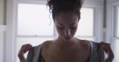 Banyo bornozunu çıkartan güzel bir kadın.