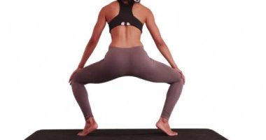 Yoga matt 'a çömelmiş melez bir kadın. Beyazların üzerine çömelen melez bir kadın. 4k