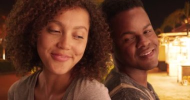Siyahi erkek ve kadın sokakta birbirlerine yaslanırlar. Afrika kökenli Amerikalı bir çift sırt sırta oturup gece araba bekliyor. 4k.