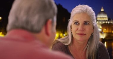 Yaşlı beyaz kadın Roma 'da tatildeyken kocasıyla sohbet ediyor. Olgun beyaz çift Roma 'da Vatikan yakınlarında bir gece konuşuyorlar. 4k