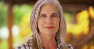 Kameraya bakan orta yaşlı, beyaz bir kadının yakın çekimi. Ciddi görünen yaşlı bir kadının portresi..