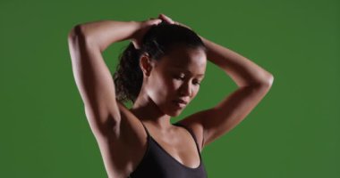 Yeşil ekranda kolları başının üzerinde duran güçlü Asyalı kadın. Anahtarlama veya birleştirme için yeşil ekranda.
