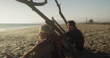 Kumsalda oturup dalgaları izleyen sevimli çiftler.