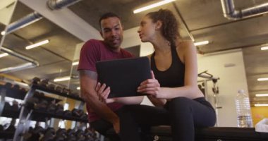Spor salonunda tablet bilgisayar kullanan mutlu siyah ve İspanyol çift