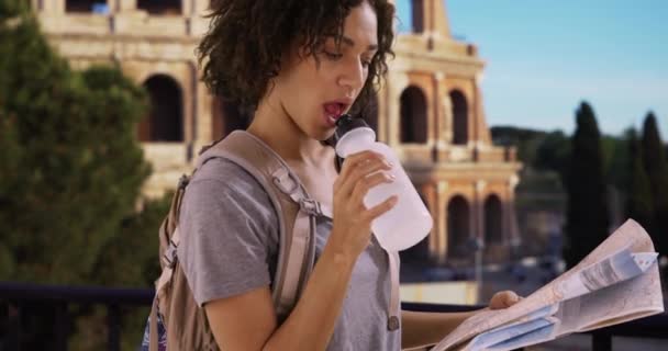 Aantrekkelijk Zwart Vrouwtje Drinkt Water Leest Kaart Bij Romeins Colosseum — Stockvideo