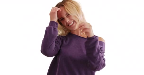 穿着宽松毛衣的年轻女士的画像 在白色的复制空间里欢快地大笑着 穿着紫色毛衣的无忧无虑的金发姑娘 带着白色背景的快乐看着相机 — 图库视频影像