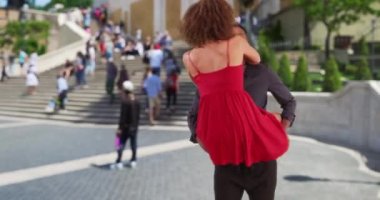 Güzel melez kadın erkek arkadaşının kollarına atlıyor. Yakışıklı siyah adam kız arkadaşını İspanyol Merdivenleri 'nin etrafında döndürüyor. 4k