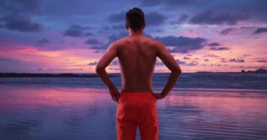 Milenyum İspanyol erkeği tropikal tatilde tatilde günbatımının tadını çıkarıyor. Karayip tatilinde okyanusta seyahat eden Latin bir turist. 4k