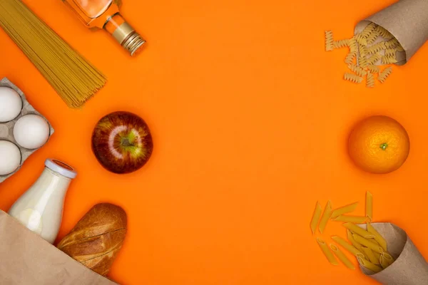 Хліб і пляшка молока в паперовій еко сумці. Спагетті, соняшникова олія, яйця і червоне яблуко — стокове фото