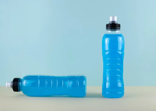 Isotonic sports drink in bottle, energy beverage on blue background.