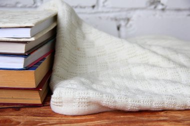 Kitap yığını ve yakındaki rahat süveter.